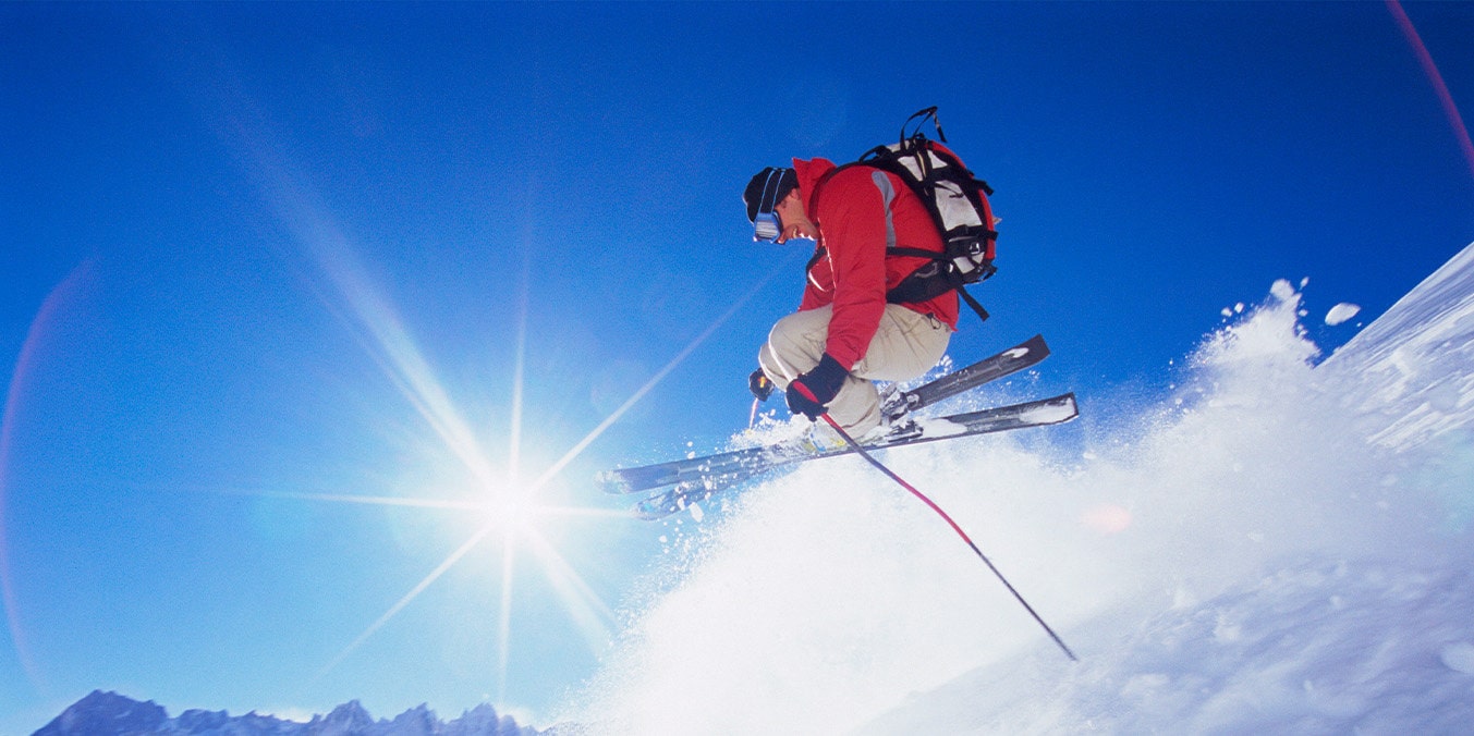 man in red jacket jumping in the air on skis