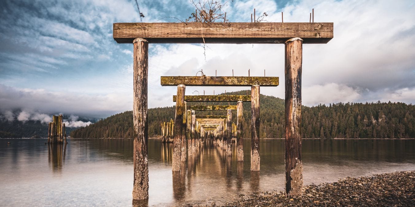 Serene waterfront scene in Burnaby with wooden structures and a backdrop of lush forests, reflecting the city's blend of natural beauty and recreational spaces, making it one of the best places to live in Vancouver