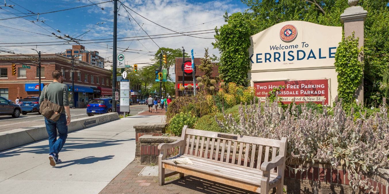 Welcome sign at the entrance of Kerrisdale in Vancouver, featuring lush greenery and a bustling street scene, illustrating its charm and appeal as one of the best places to live in Vancouver