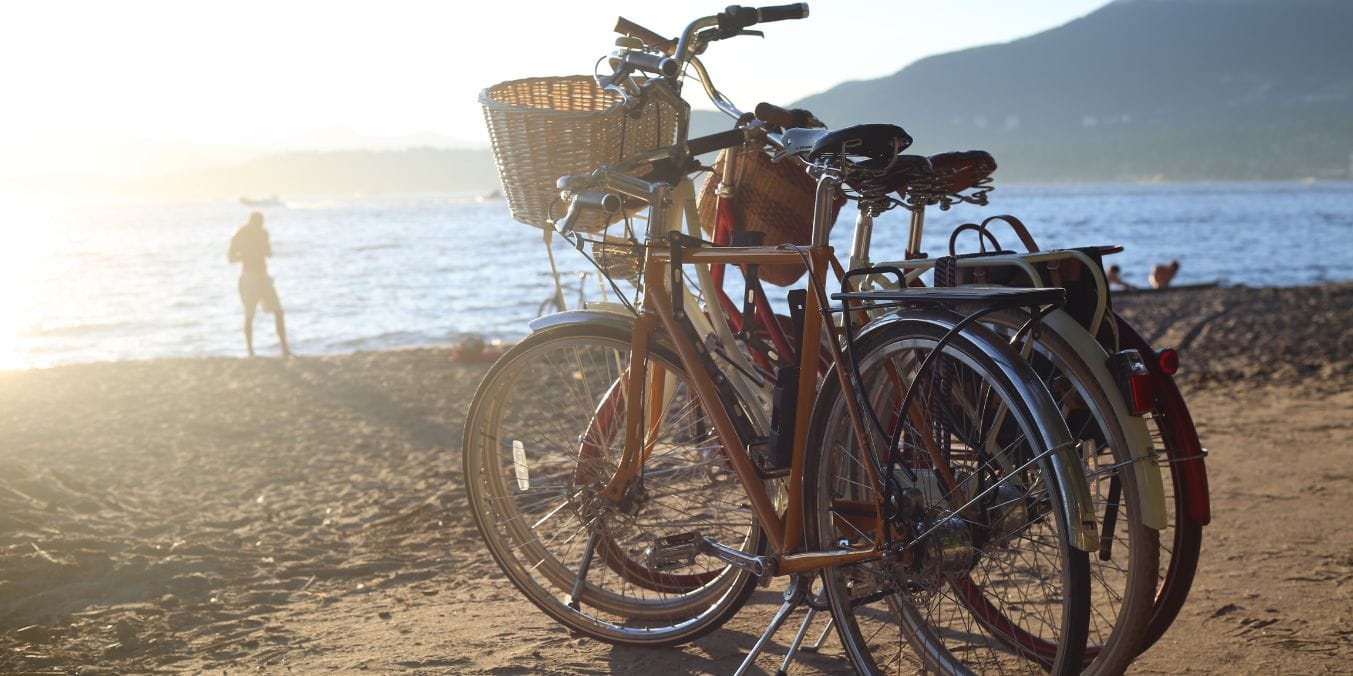 Bicycles parked on a Vancouver beach at sunset, highlighting popular outdoor activities in the city with ocean and mountain views.