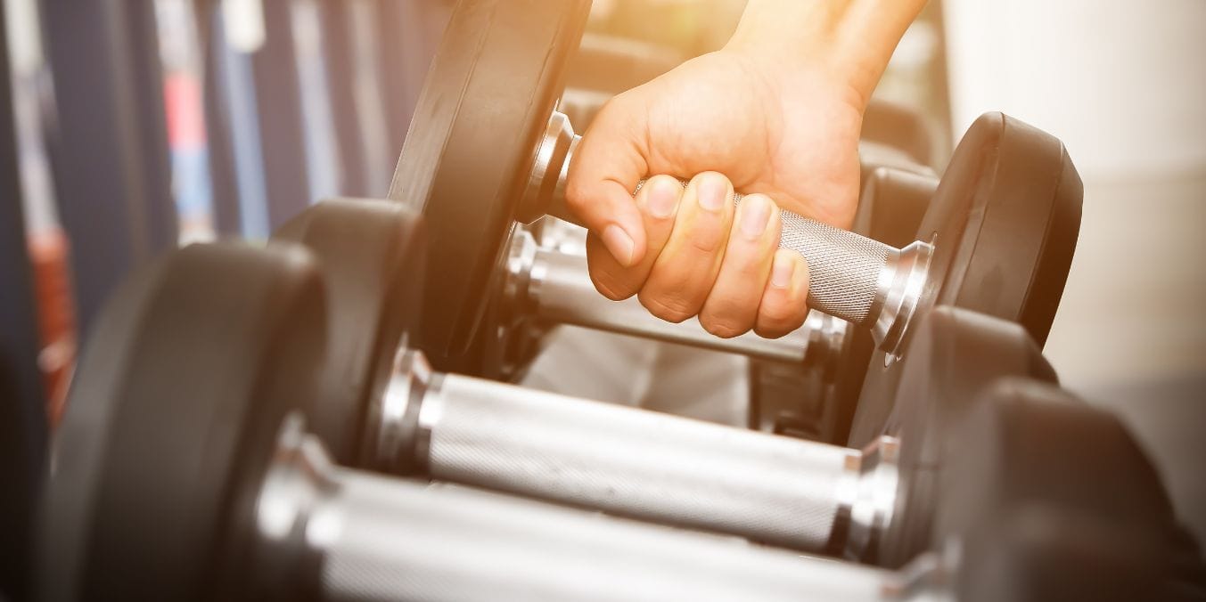 Close-up of a hand lifting a dumbbell in a gym, illustrating the range of gym membership costs in Vancouver from standard to specialty fitness centers