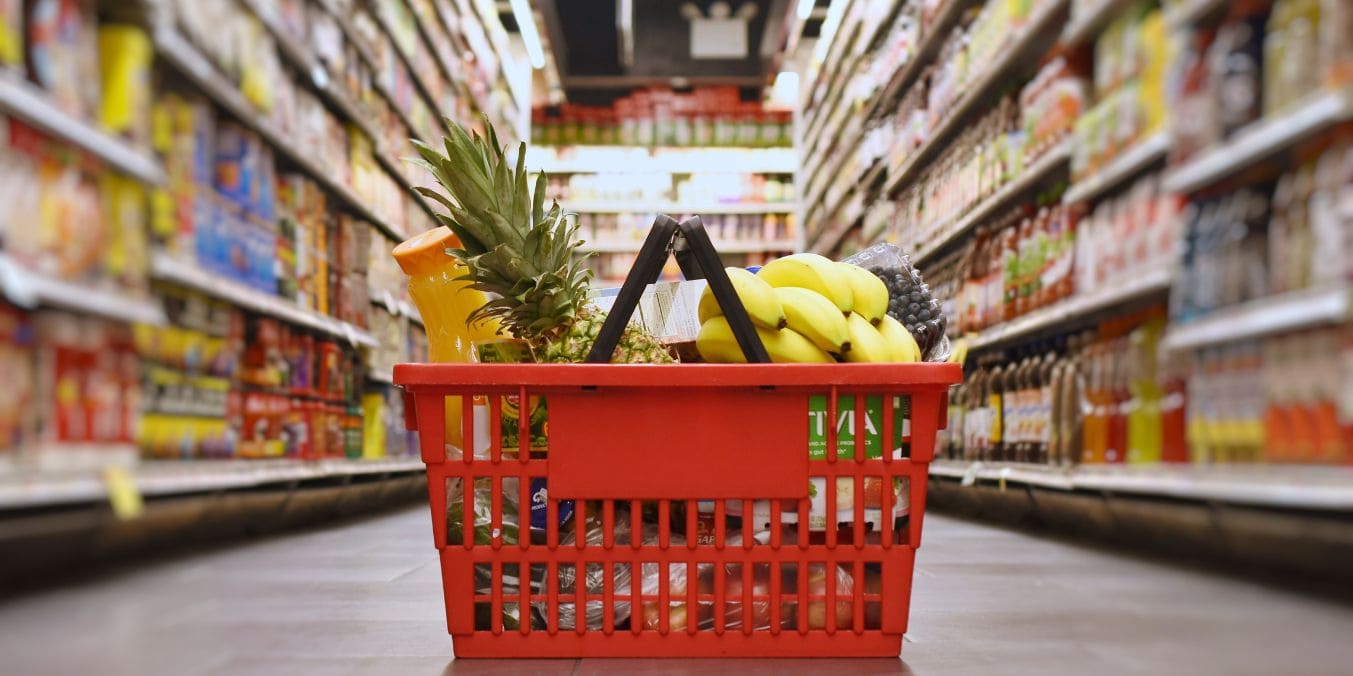 Shopping cart filled with groceries in a Vancouver supermarket aisle, highlighting the high cost of everyday essentials in the city as a factor in its expensive living costs