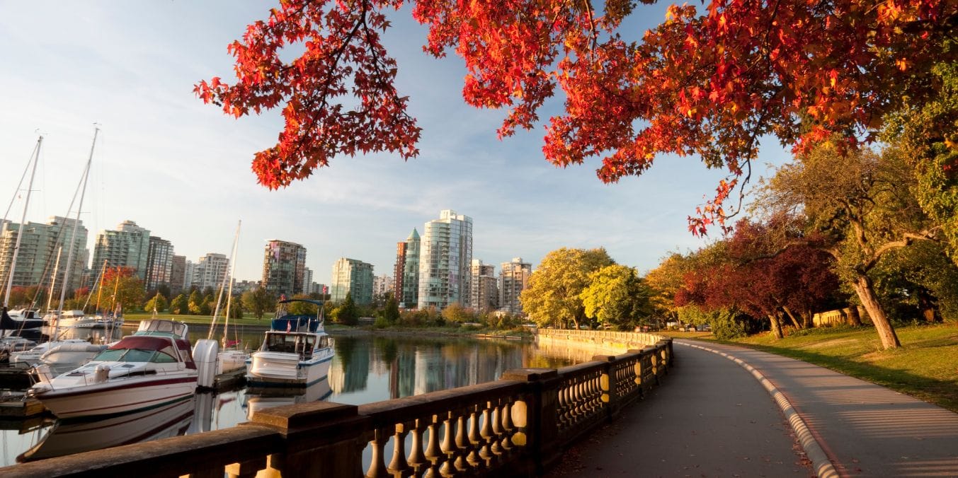 Autumn view of Stanley Park with vibrant foliage and Vancouver skyline, showcasing the natural landscapes the city is famous for.