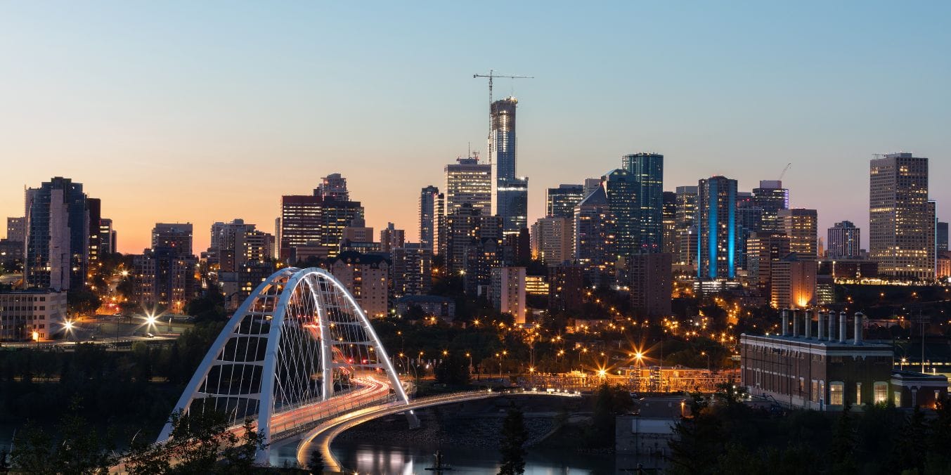 The skyline of Downtown Edmonton at dusk, featuring towering skyscrapers and the iconic Walterdale Bridge, highlights as one of the best neighborhoods.