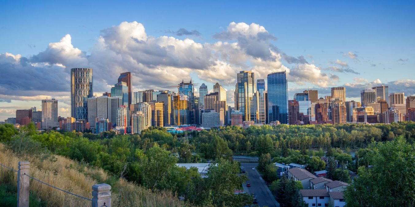 A scenic view of the Calgary skyline contrasted with Winnipeg, highlighting the geographic and climatic differences between the two Canadian cities