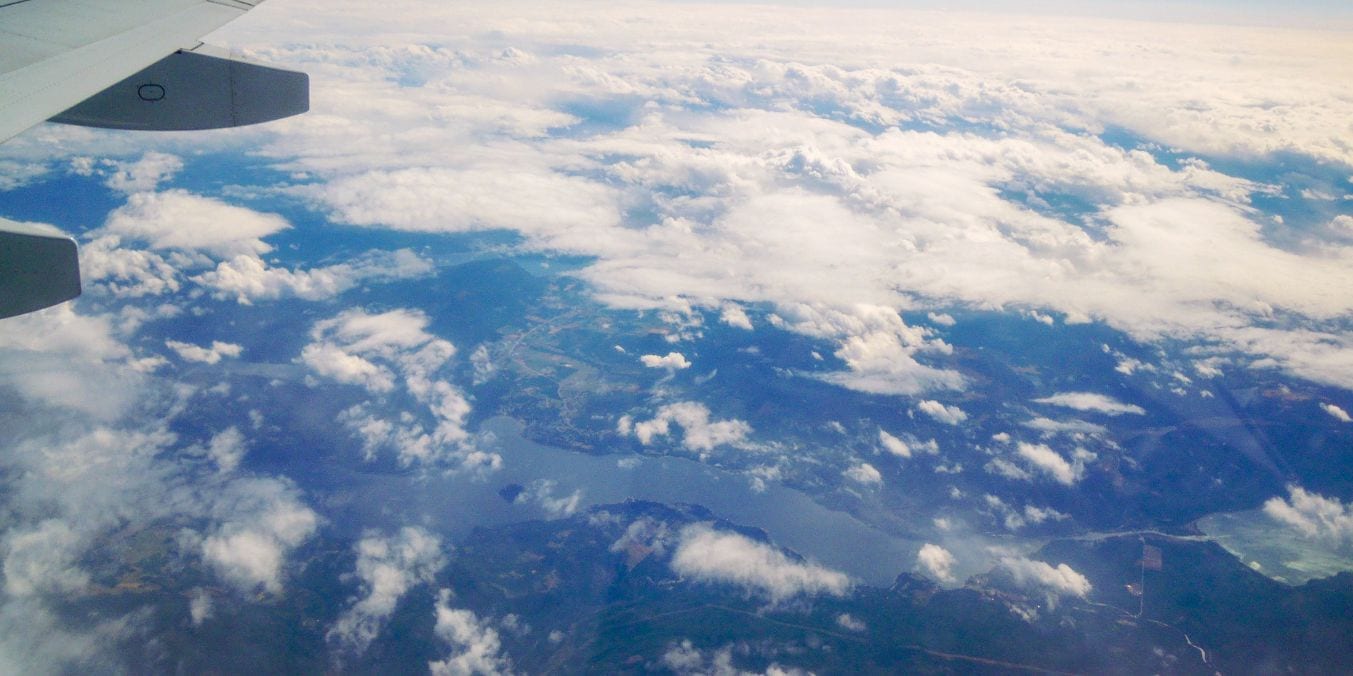 View from an airplane showing the diverse landscapes of Edmonton's flatlands and Vancouver's coastal, mountainous terrain.