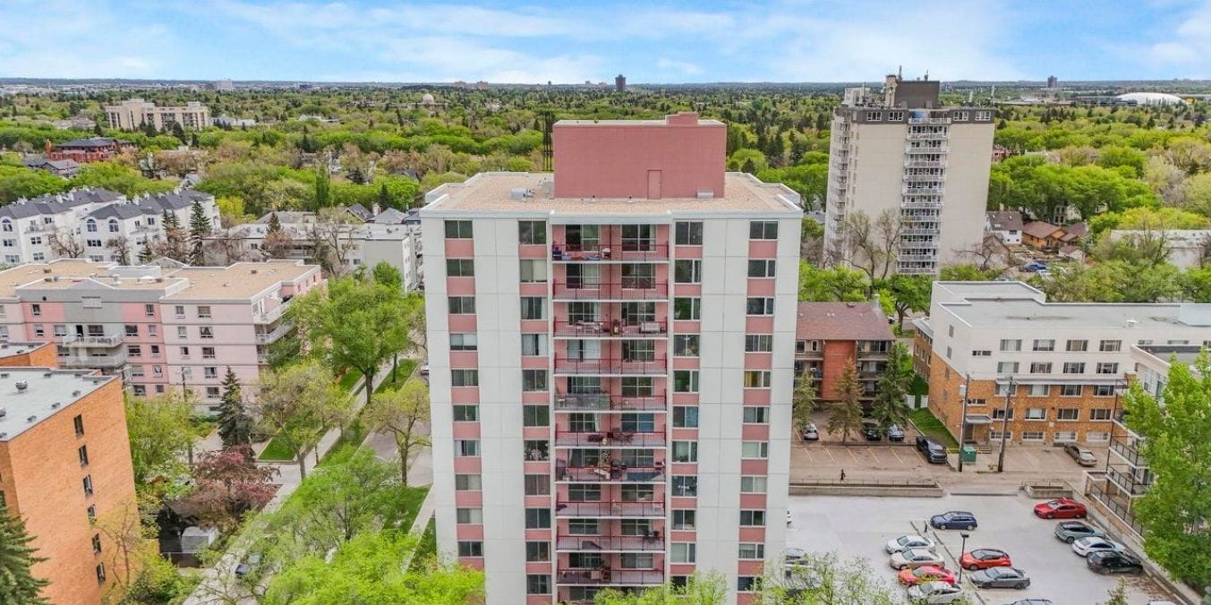 Aerial view of residential buildings in Garneau, Edmonton, surrounded by lush greenery, with a clear sky in the background, highlighting as one of the best neighborhoods.