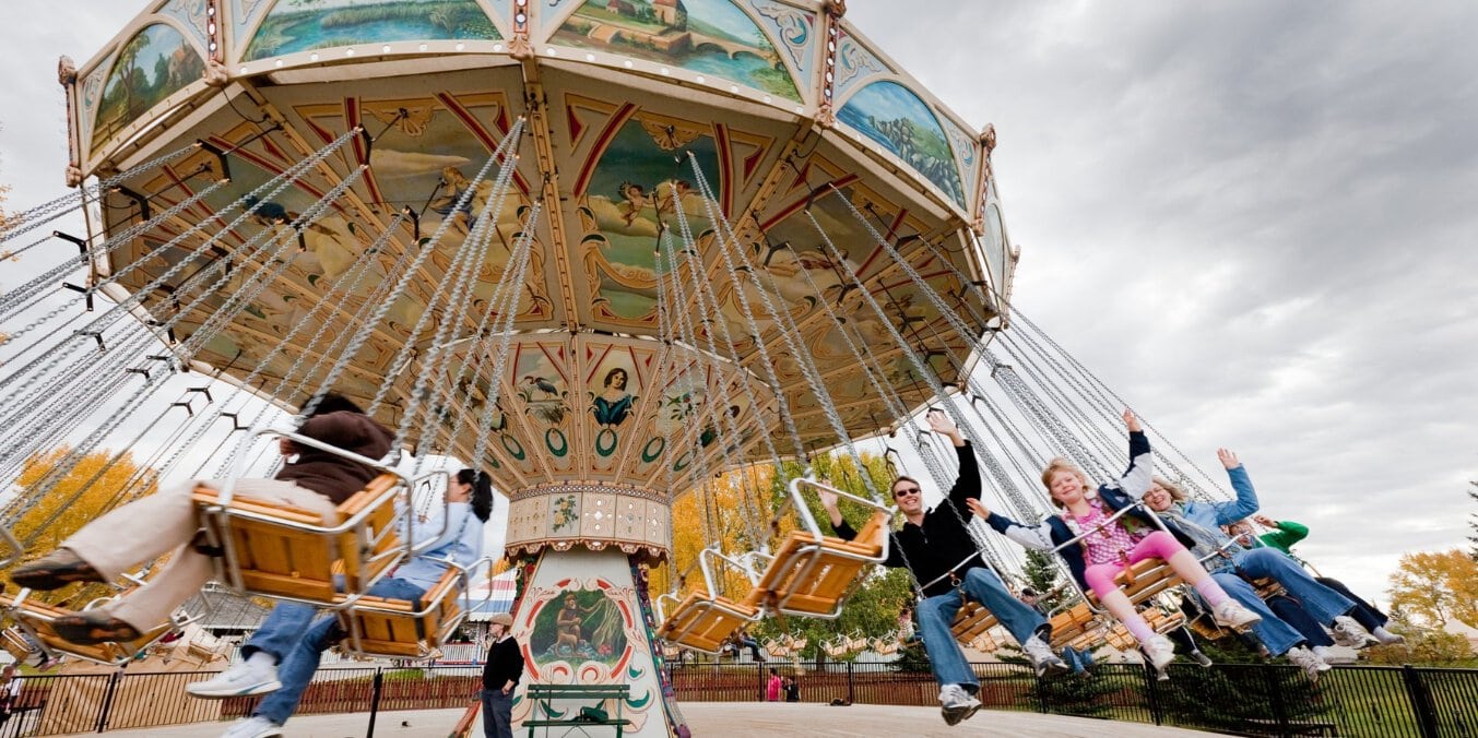 Visitors enjoying a vintage swing ride at Heritage Park Historical Village, showcasing what Calgary is known for in historical attractions