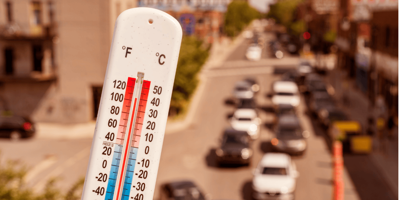 A thermometer displaying high temperatures with a blurred background of a busy city street, illustrating climate and weather differences when comparing living in Calgary vs Toronto.