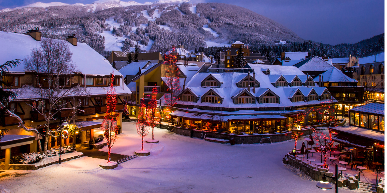 A snowy winter evening in a charming village with festive lights, cozy buildings, and snow-covered mountains in the background, illustrating dining and nightlife when comparing living in Calgary vs Toronto.