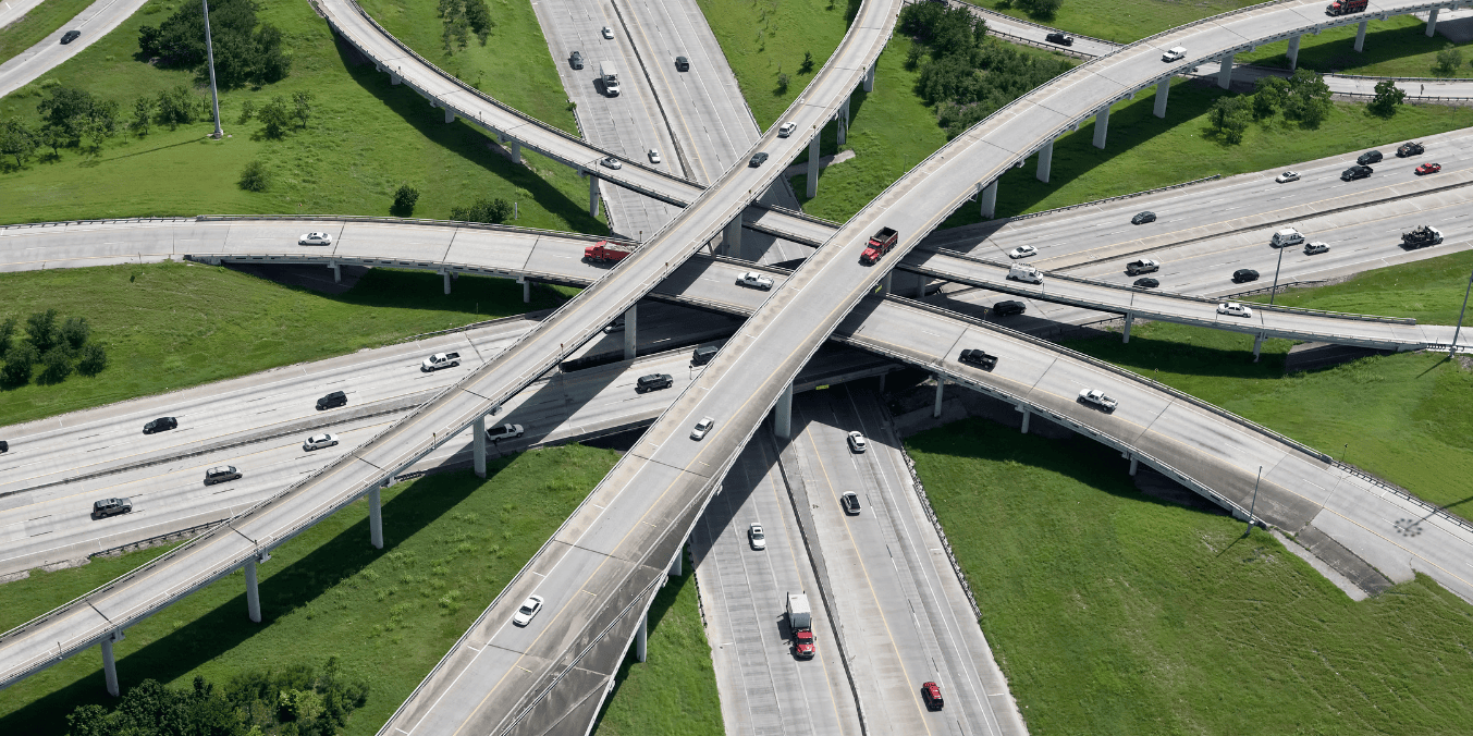 Aerial view of a multi-level highway interchange with cars moving in various directions, illustrating transportation and infrastructure when comparing living in Calgary vs Toronto.