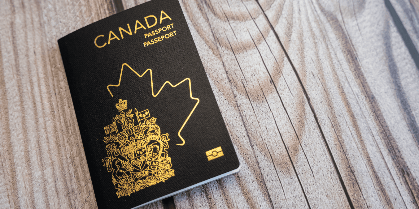 Canadian passport with gold emblem on a wooden surface, symbolizing travel and immigration to Canada.