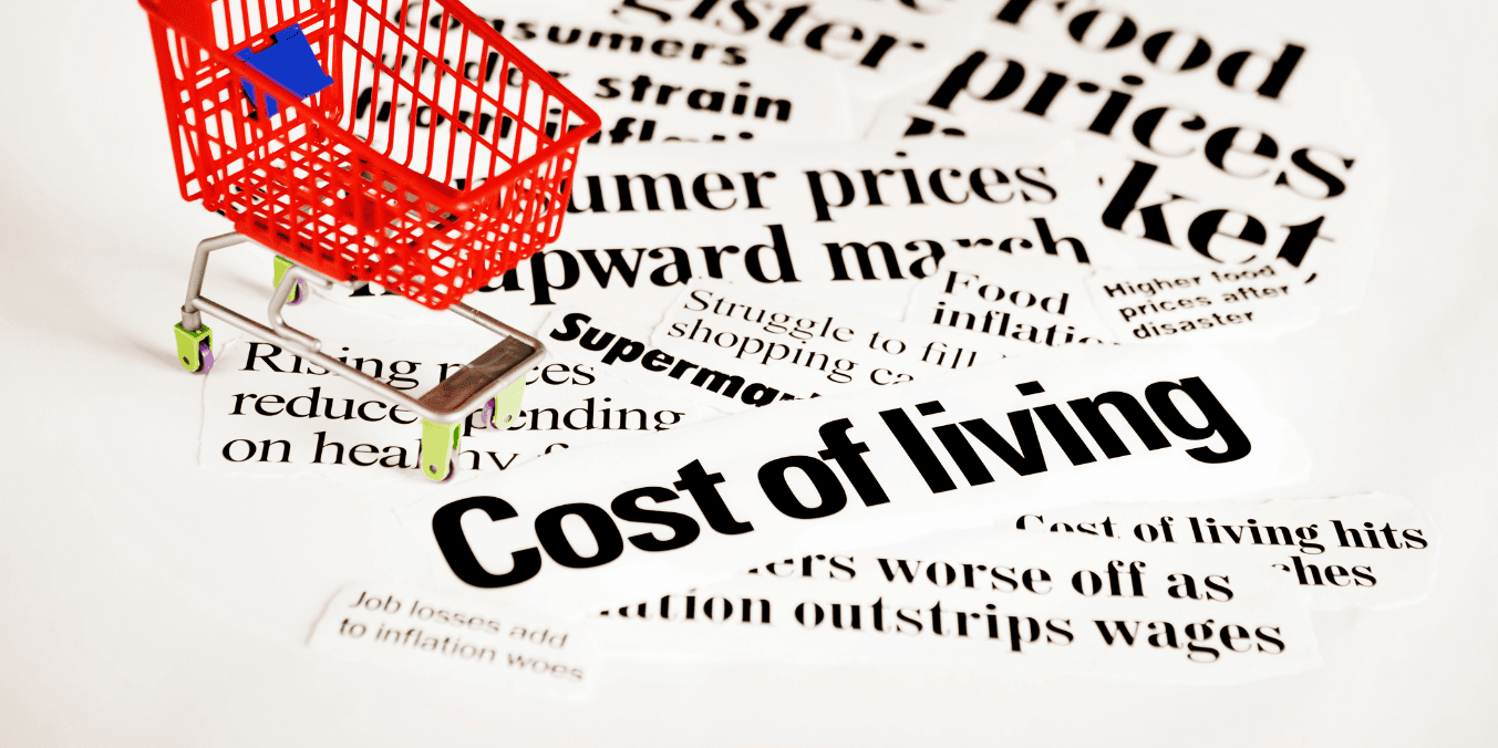 A miniature shopping cart surrounded by various newspaper clippings about the cost of living, highlighting the financial considerations when comparing living in Calgary vs Toronto.