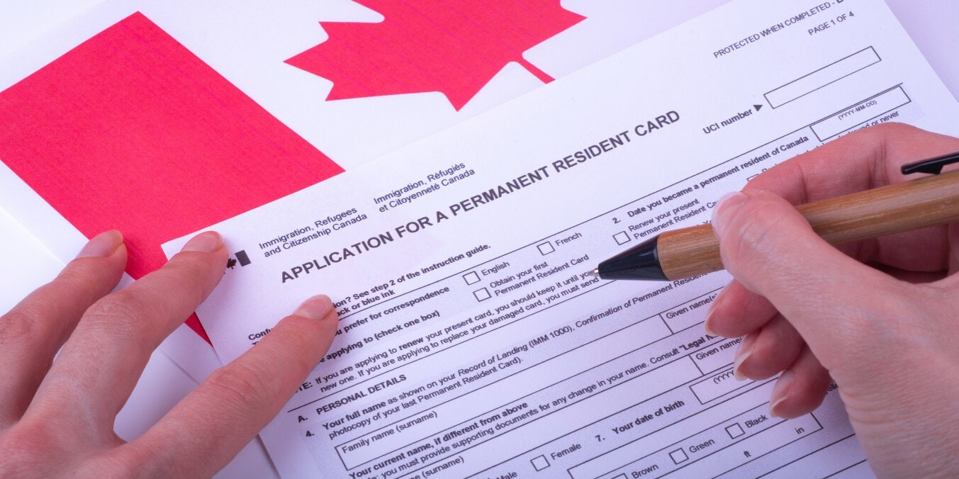 Female hands fill Canadian citizenship form Express Entry on Canadian flag