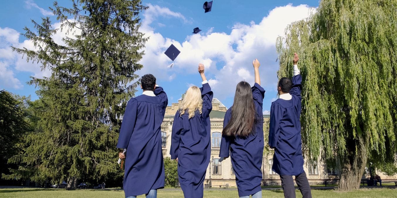 Graduates in blue gowns celebrating by throwing caps in the air, symbolizing the educational opportunities in Montreal vs Toronto.