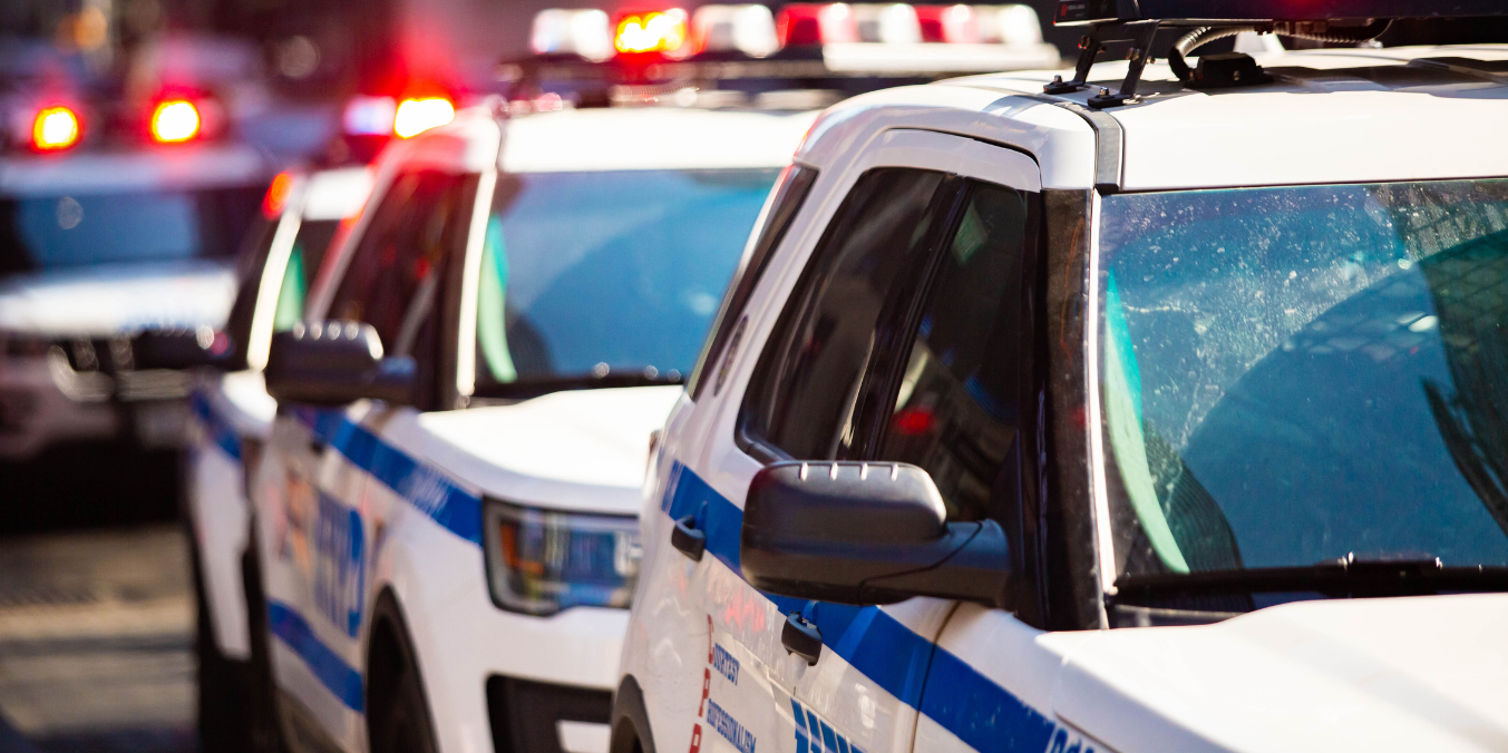 A row of police vehicles with flashing lights, lined up on a city street, relevant to the Alberta PR program.