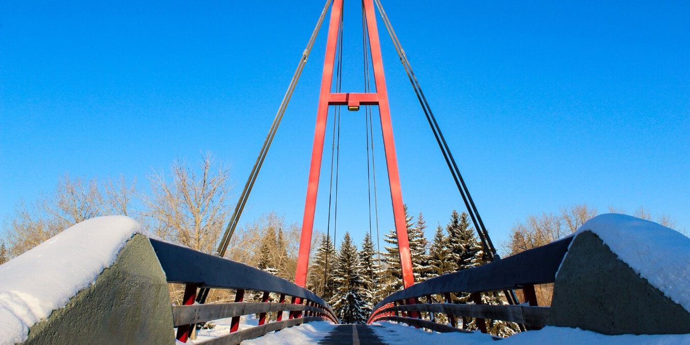 Red pedestrian bridge in St. Albert during winter, showcasing why St. Albert is the best place to live in Alberta