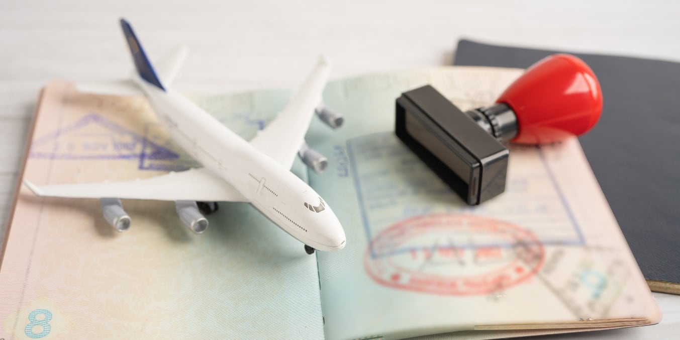 Travel documents with a plane model and visa stamp, representing visa options for finding the best place to live in Alberta