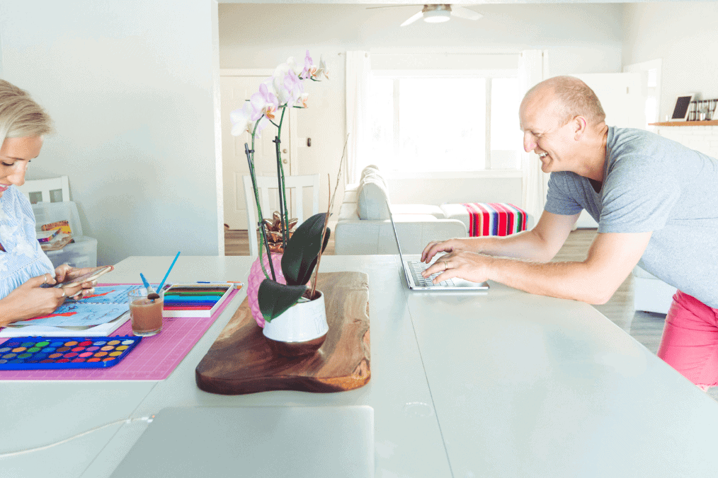 A couple working from home, with the woman painting and the man using a laptop, illustrating a shared space while discussing SOWP (Spousal Open Work Permit) options