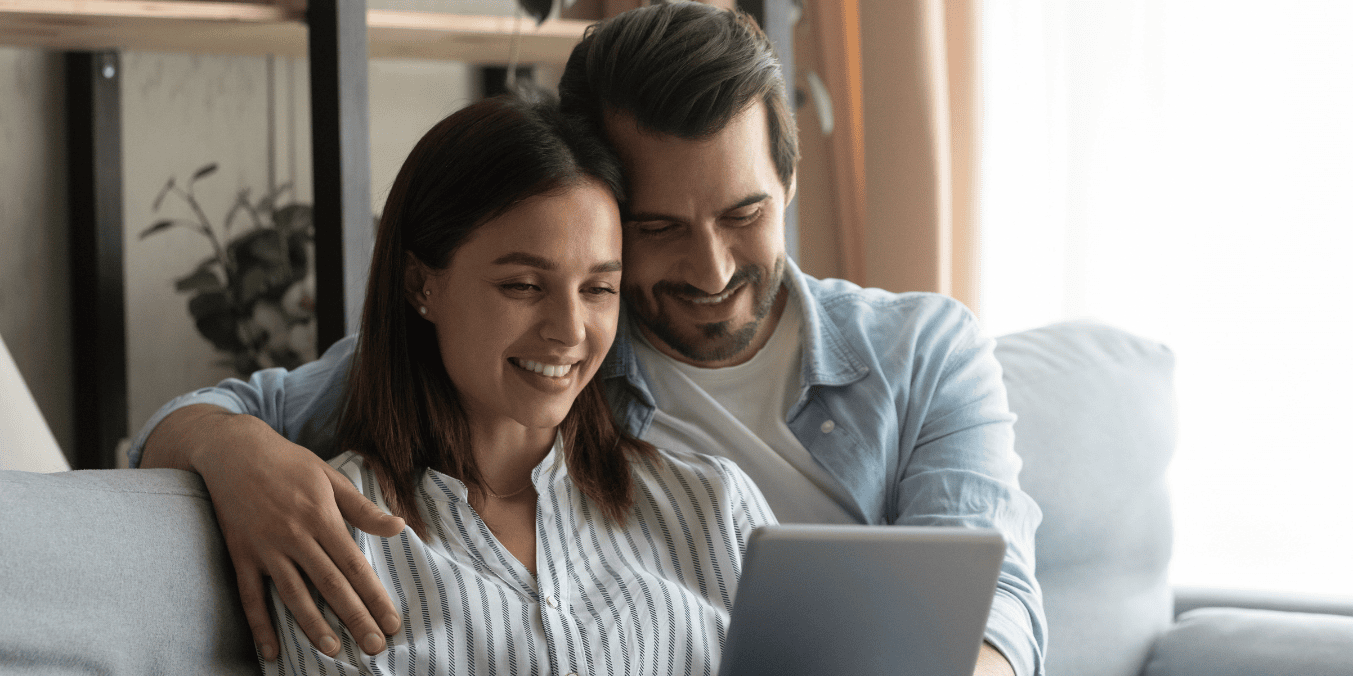 A happy couple researching how long spousal sponsorship takes in Canada on a tablet