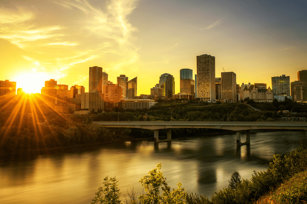 Sunset over downtown Edmonton skyline with a bridge crossing the river, highlighting the best places to live in Edmonton for families.