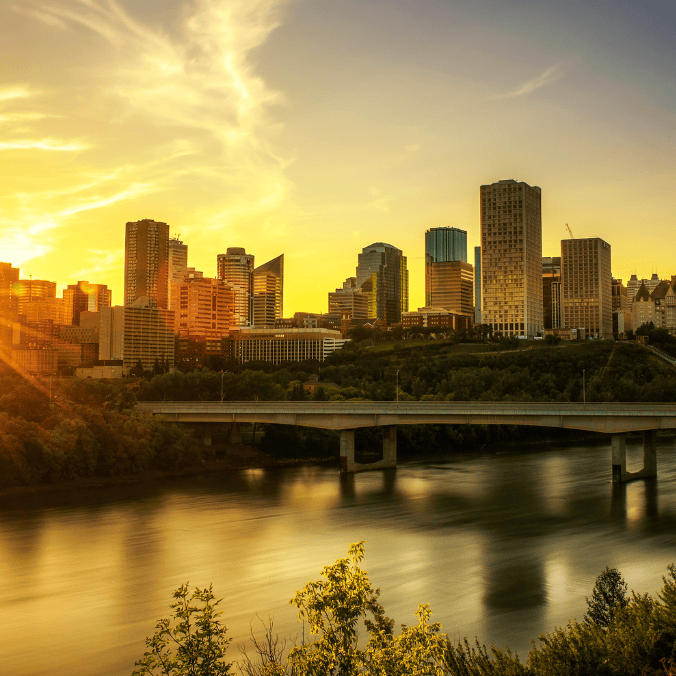 Sunset over downtown Edmonton skyline with a bridge crossing the river, highlighting the best places to live in Edmonton for families.