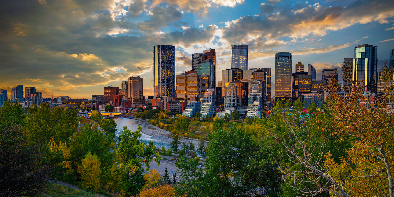 Edmonton city skyline at sunset with lush trees and a river in the foreground, highlighting the best places to live in Edmonton for families.