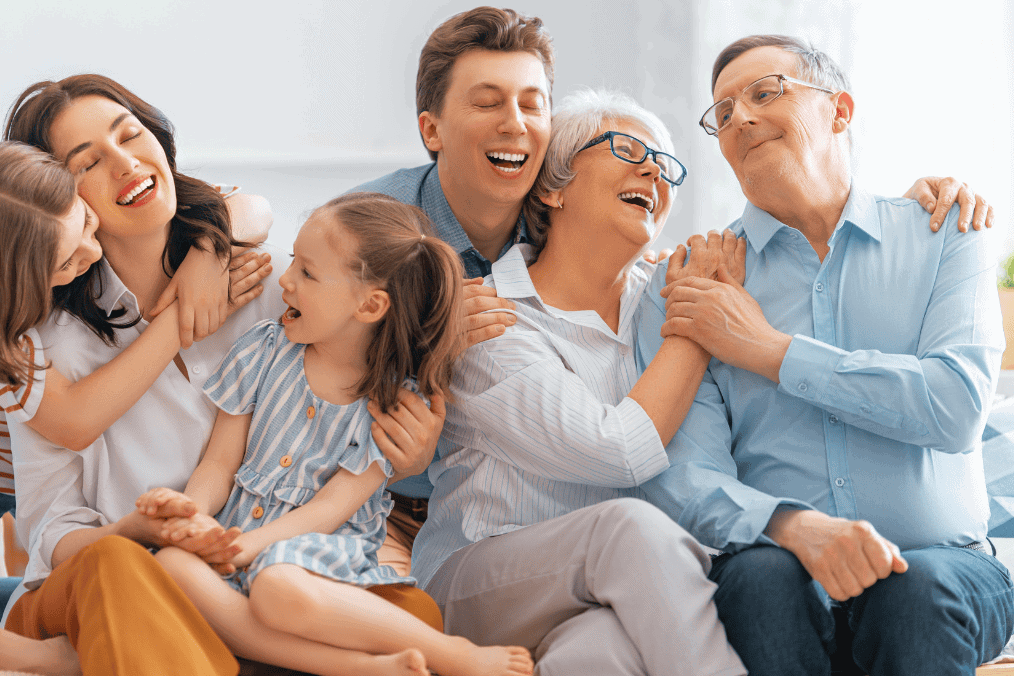 Multigenerational family smiling and embracing each other, symbolizing family sponsorship and reunification in Canada amidst new immigration targets for 2025-2027.