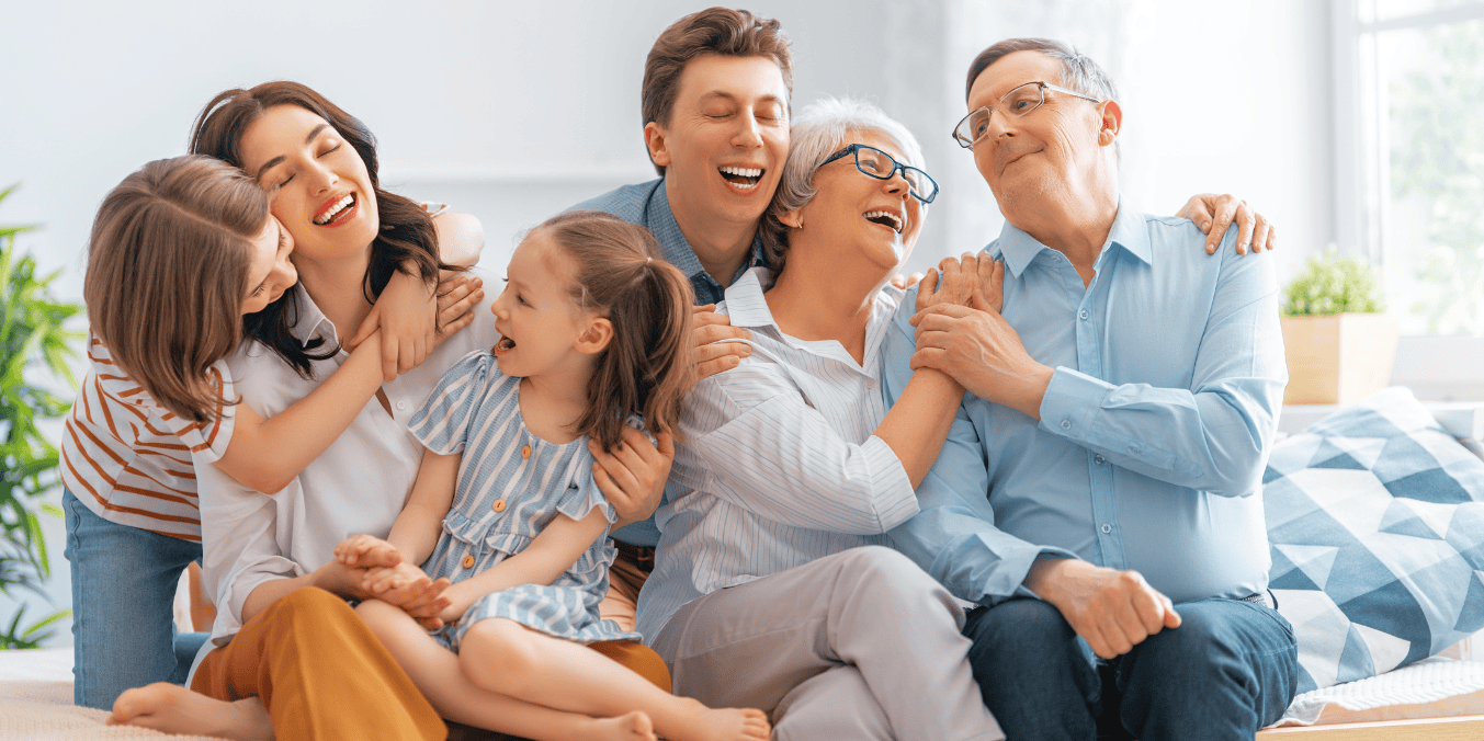 Multigenerational family smiling and embracing each other, symbolizing family sponsorship and reunification in Canada amidst new immigration targets for 2025-2027.