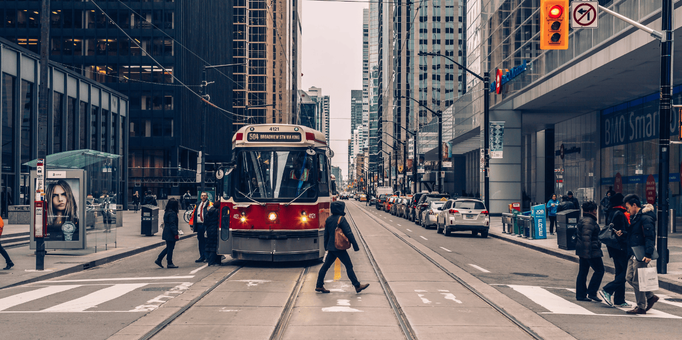 Downtown Toronto street with a streetcar and pedestrians, depicting urban life for newcomers interested in how much bank balance is required for Canada immigration.