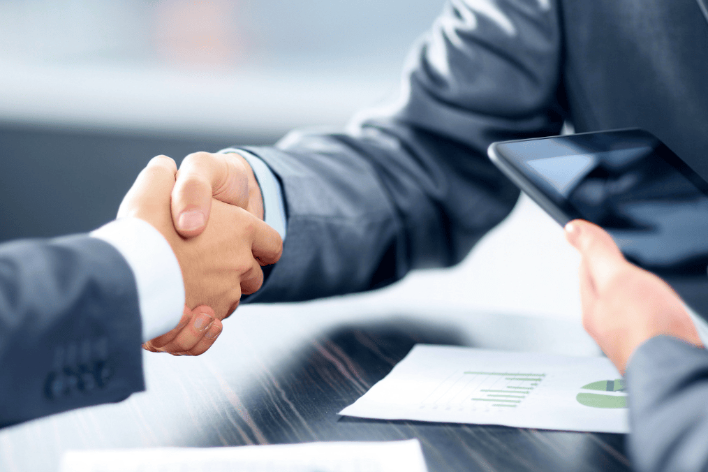 Business handshake with tablet and documents, representing sponsorship agreement in Canada. How long are you financially responsible for someone you sponsor in Canada?