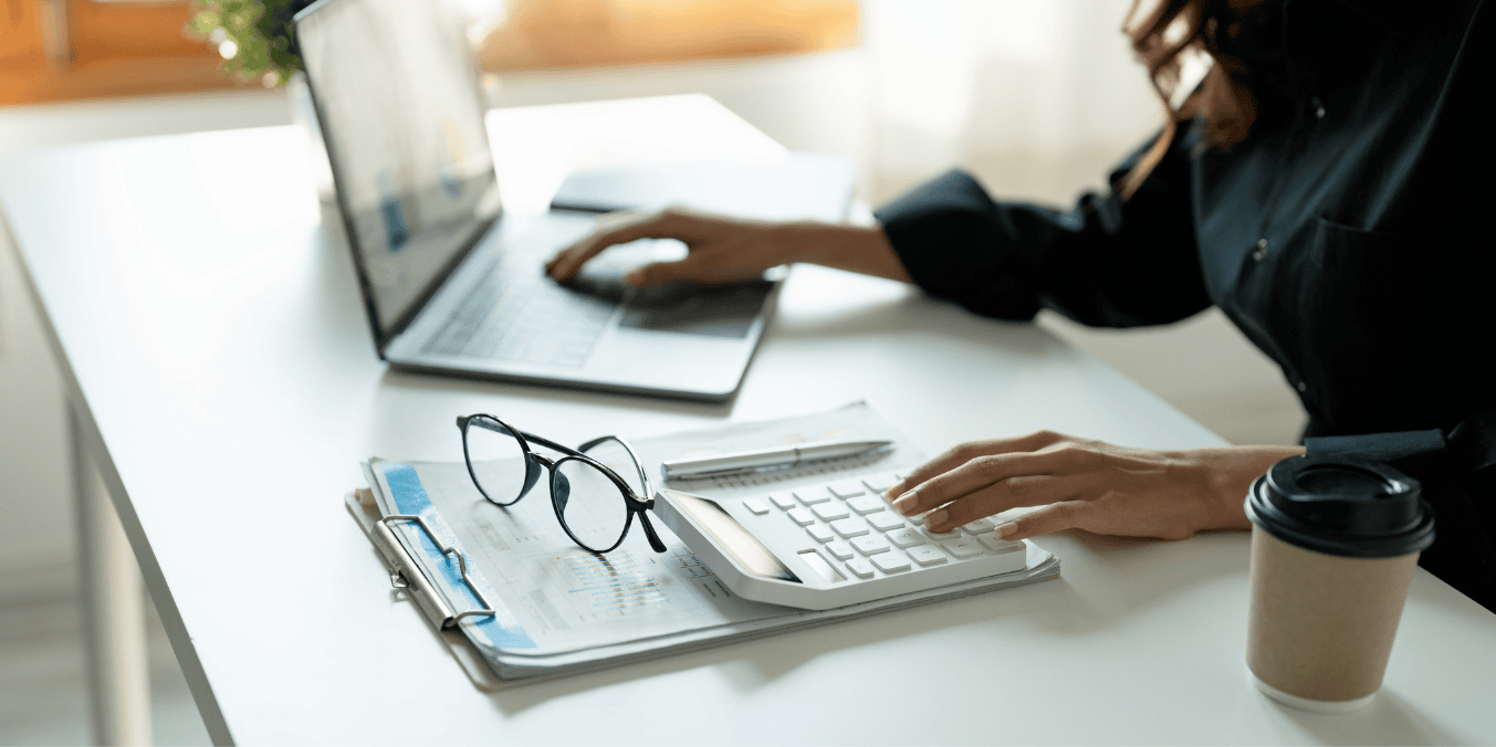 Person calculating finances at a desk with a laptop. How long are you financially responsible for someone you sponsor in Canada?