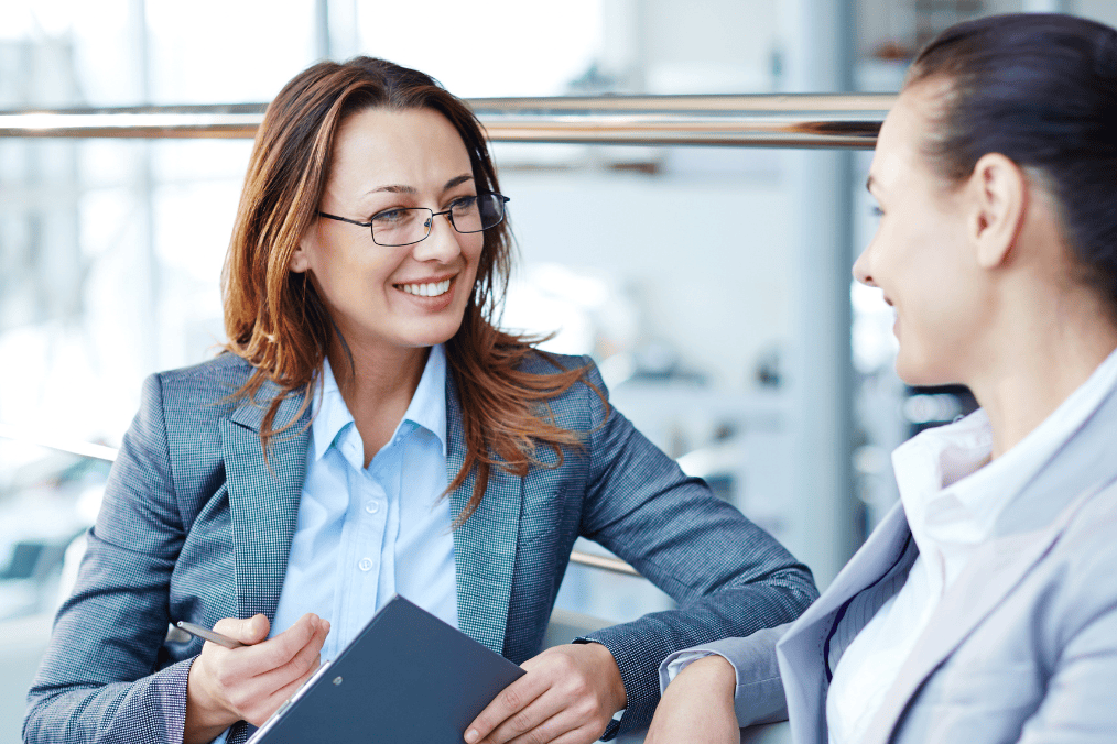 Two professional women discussing how to choose a Canadian immigration consultant during a business meeting.