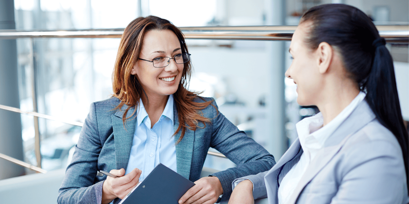 Two professional women discussing how to choose a Canadian immigration consultant during a business meeting.