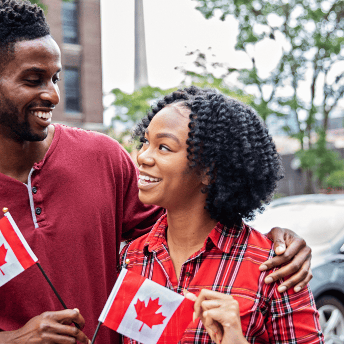 Is Calgary immigrant friendly? A happy couple holding Canadian flags smiles as they enjoy their new life in Calgary, showcasing the city's welcoming atmosphere and supportive environment for newcomers.