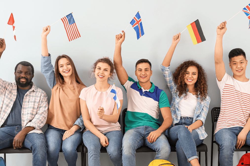 A group of international students meeting language requirements for Express Entry to Canada, each holding flags representing different countries, symbolizing diversity in language proficiency and immigration pathways.