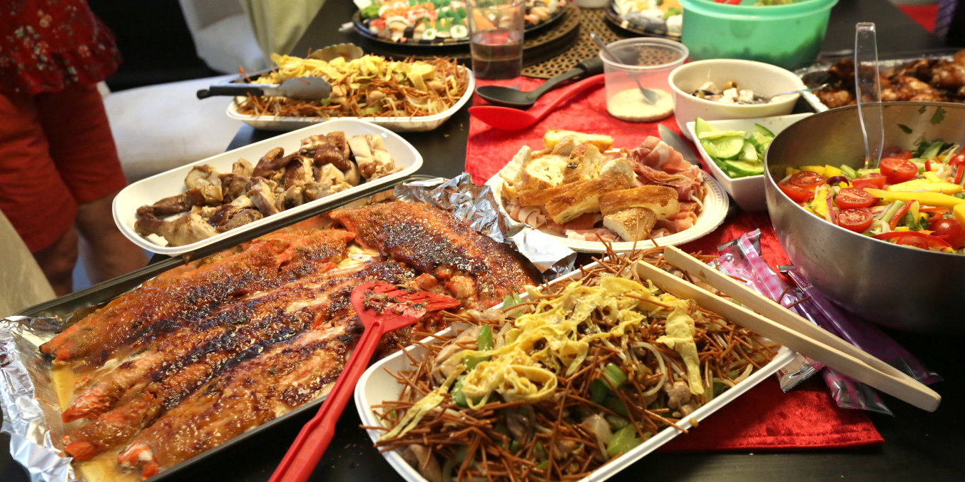 A delicious spread of diverse dishes including grilled fish, salads, noodles, and meats, showcasing the variety of culinary influences and food culture. This image highlights the importance of food in daily life and reflects the dining experiences when comparing life in Canada vs France.