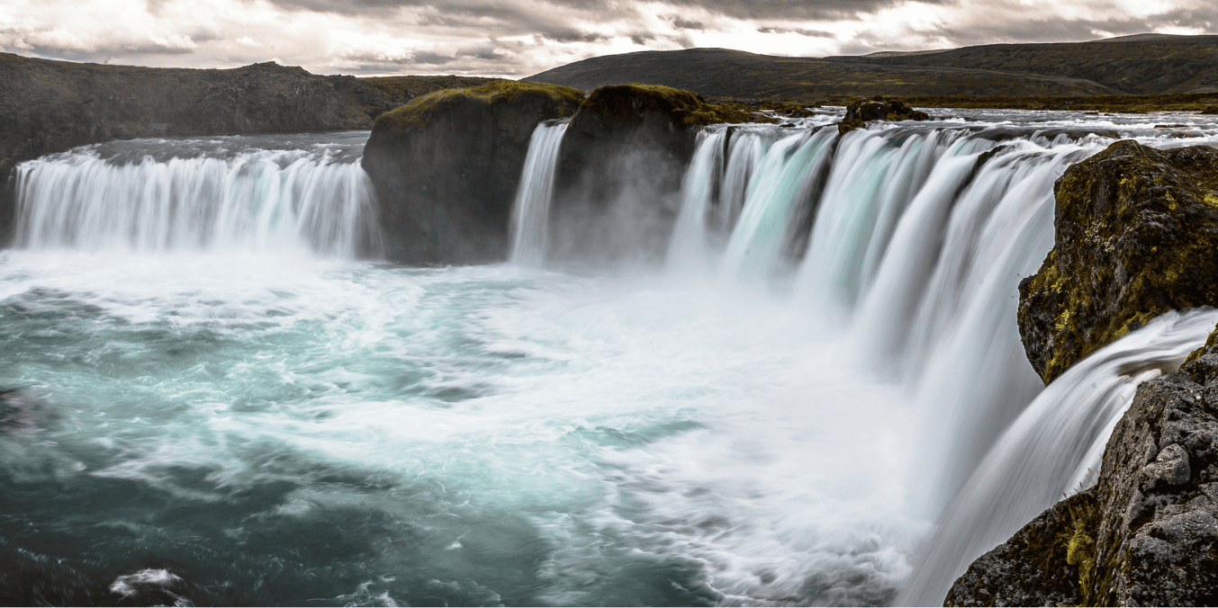 A stunning view of a powerful waterfall surrounded by rocky cliffs and mist, showcasing the natural beauty and outdoor landscapes often highlighted in the comparison of life in Canada vs France.