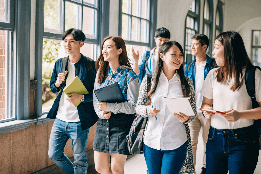 International students discussing their studies while walking through a university hallway, preparing for PGWP eligibility in Canada.