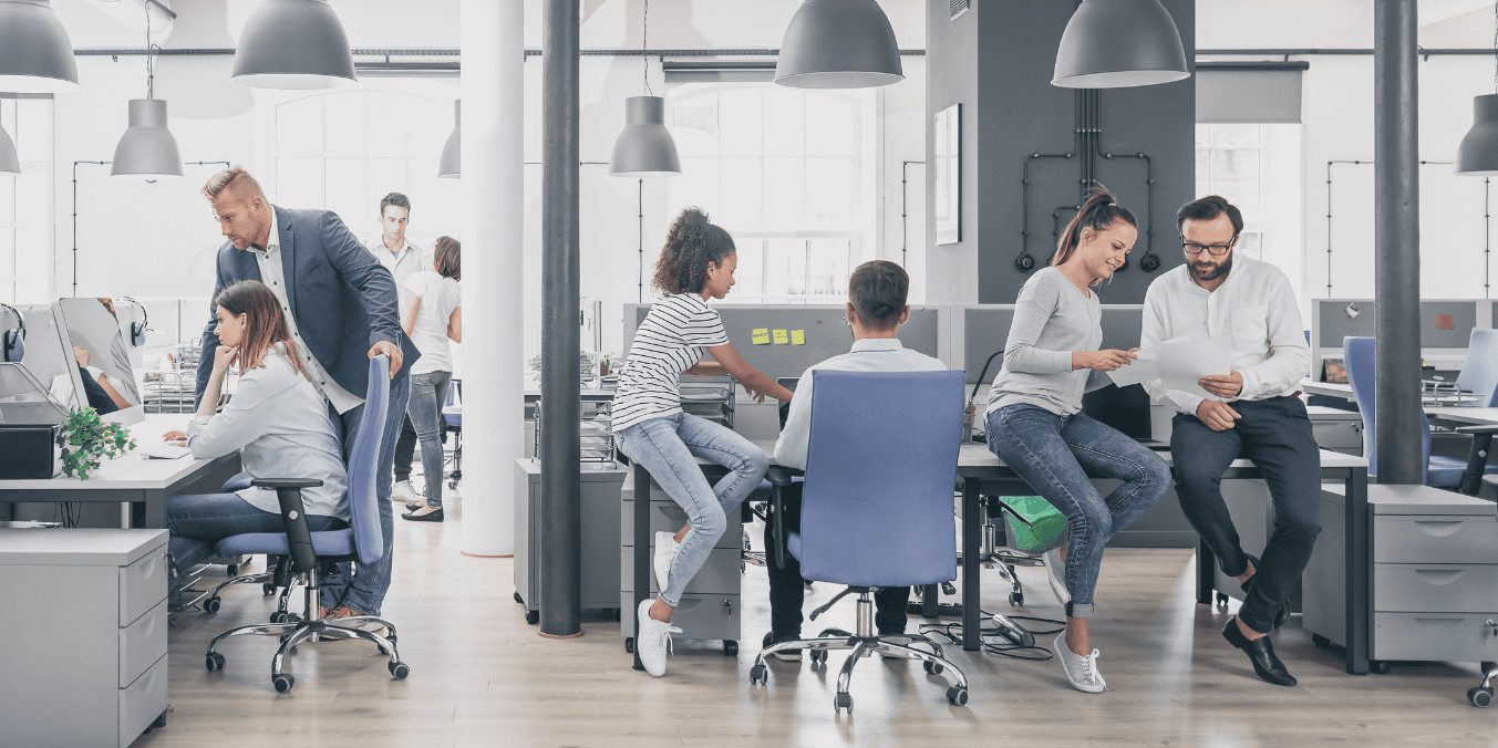 Modern office with people collaborating, discussing projects, and working at desks. Bright space, suitable for LMIA-exempt job roles.