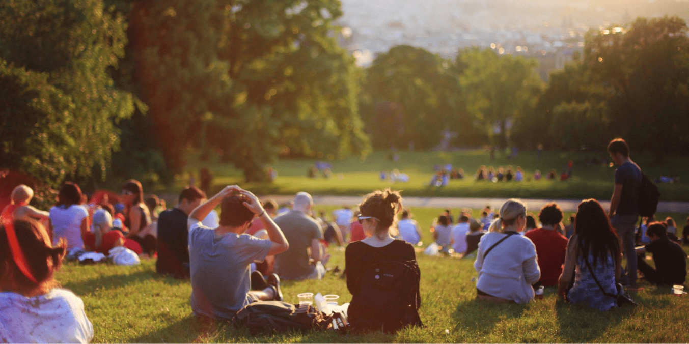 A large group of people socializing and relaxing in a park, representing the community connections formed through Vancouver social groups.