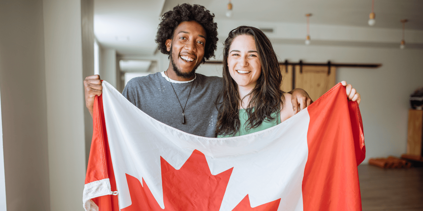 Happy couple holding a Canadian flag, celebrating the advantages of Canadian citizenship.