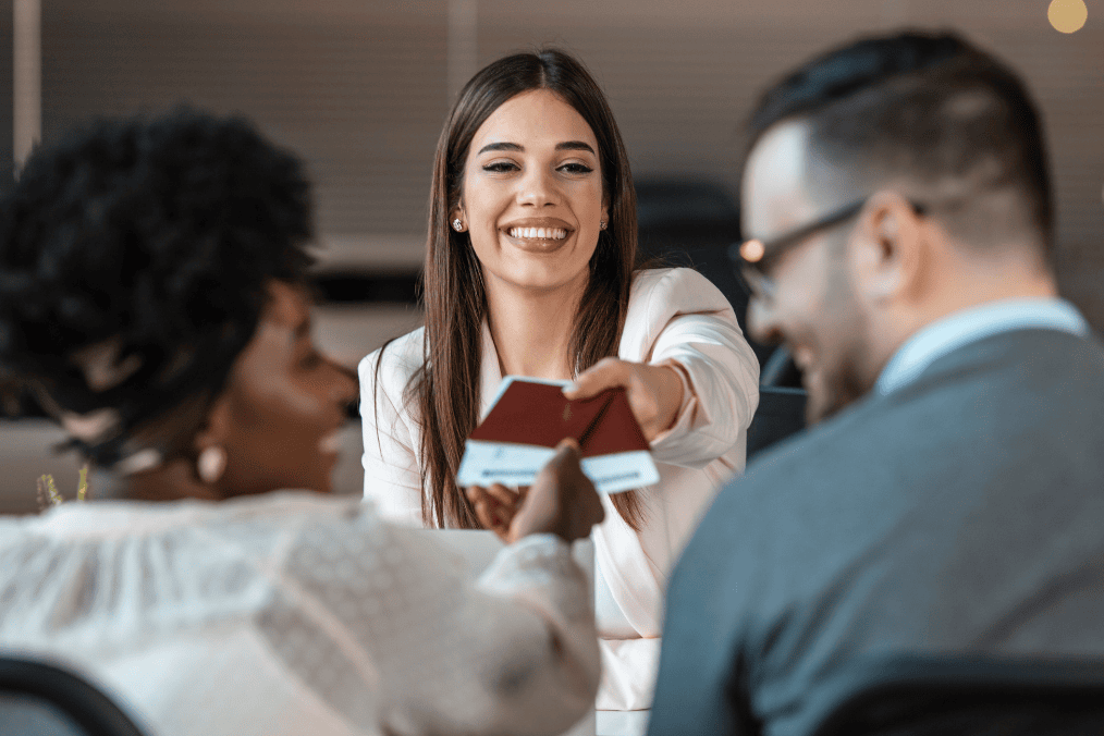 Smiling immigration consultant handing passports to a couple, symbolizing successful Super Visa application process in Canada.