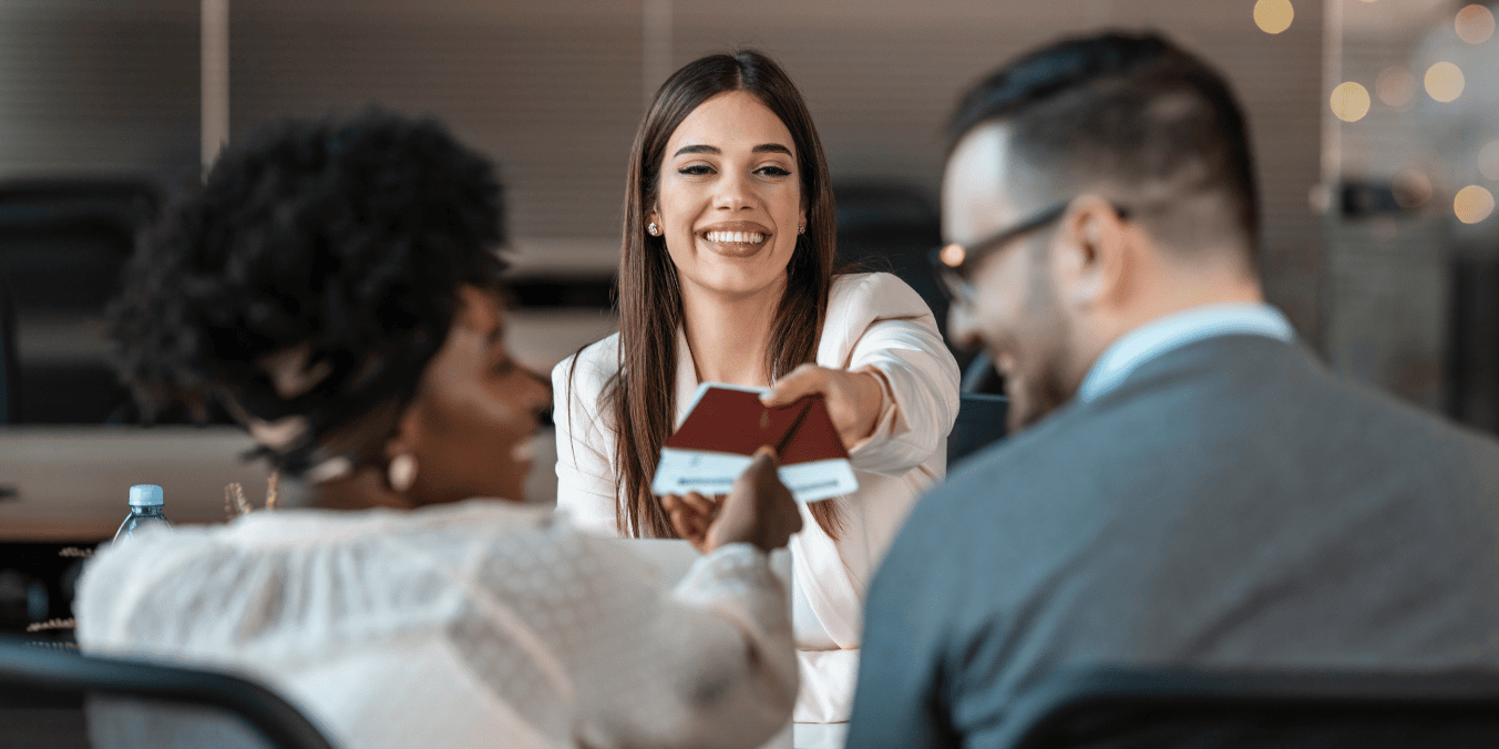 Smiling immigration consultant handing passports to a couple, symbolizing successful Super Visa application process in Canada.