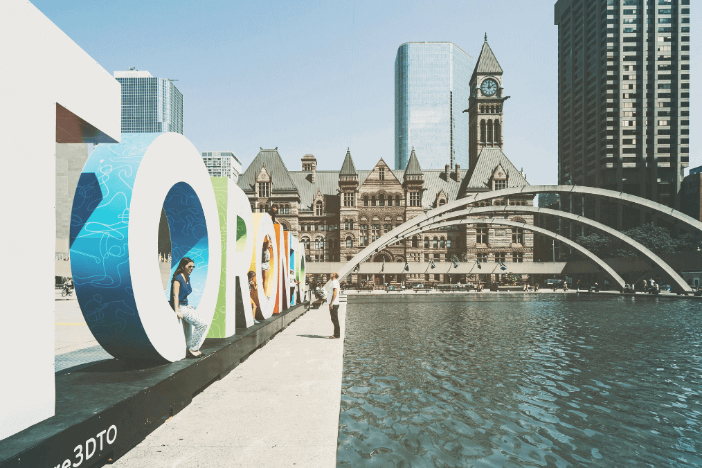 Toronto sign at Nathan Phillips Square with Old City Hall, a key destination for immigrants in Canada’s Express Entry draw system.