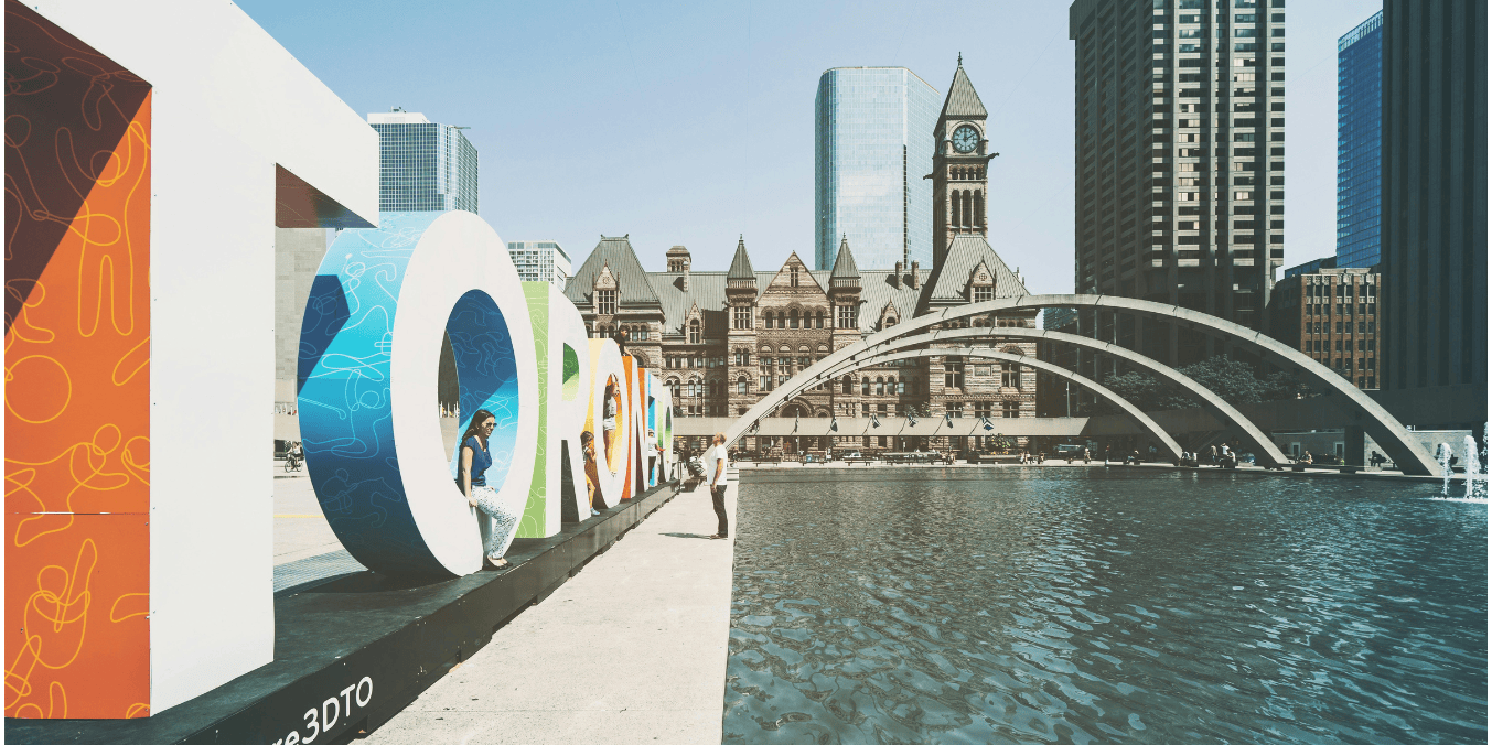 Toronto sign at Nathan Phillips Square with Old City Hall, a key destination for immigrants in Canada’s Express Entry draw system.