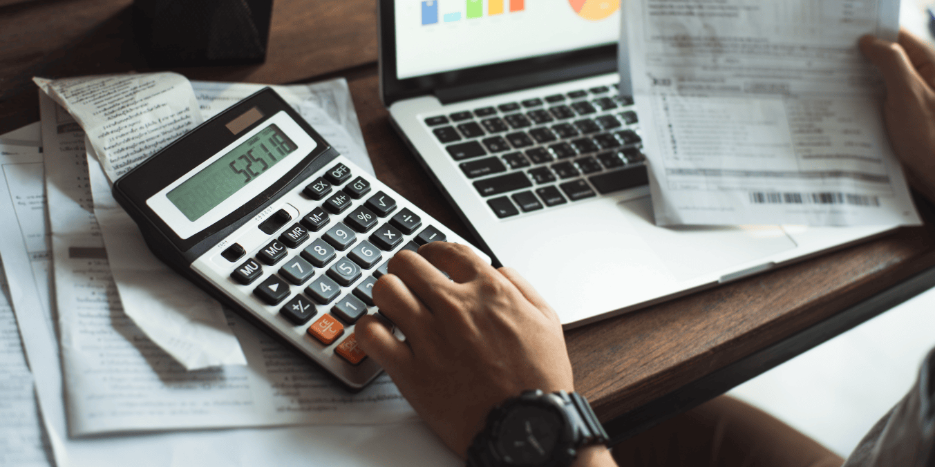 Calculating LMIA costs with a calculator, financial documents, and a laptop displaying charts – understanding how much does LMIA cost.