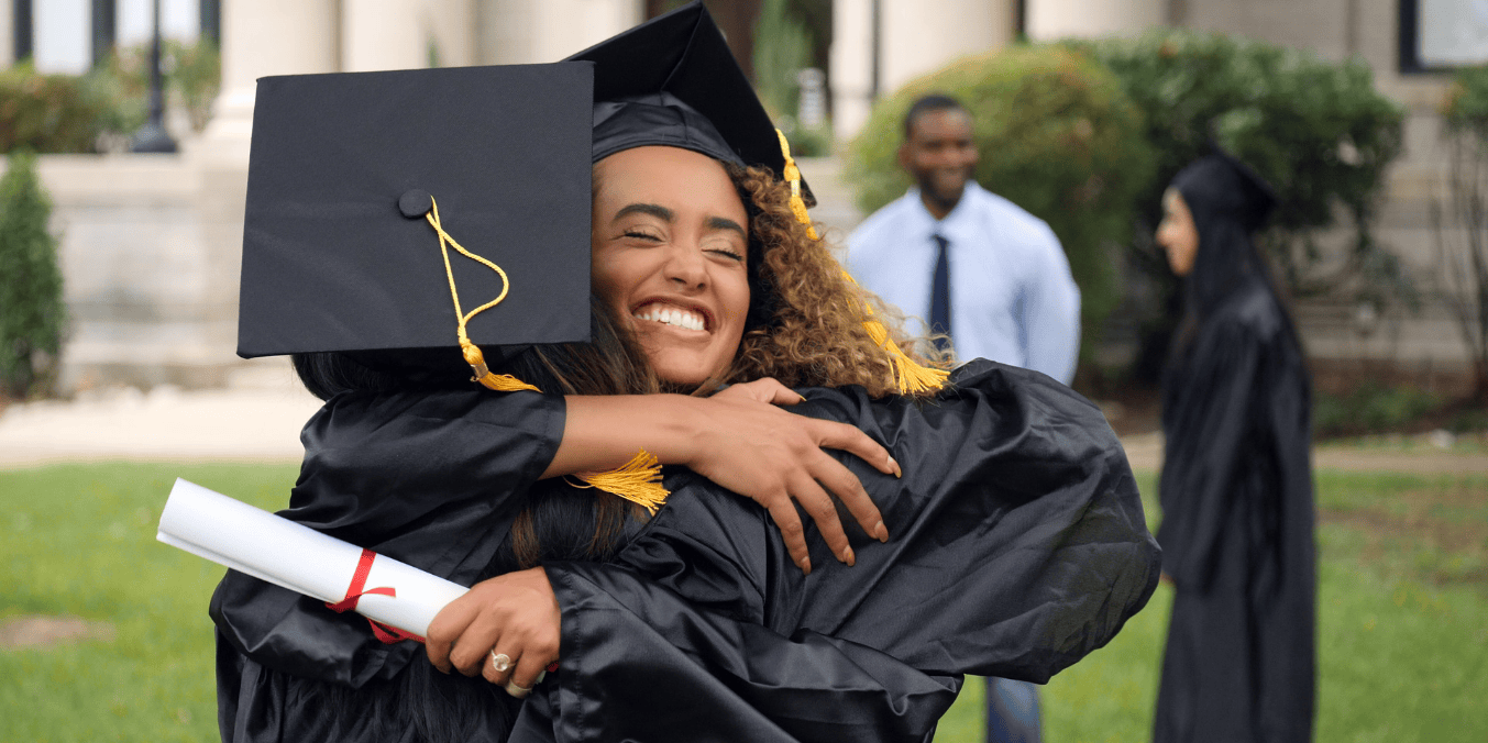 Two graduates celebrating in caps and gowns, holding a diploma, on graduation day—ready to meet PGWP requirements for work in Canada.